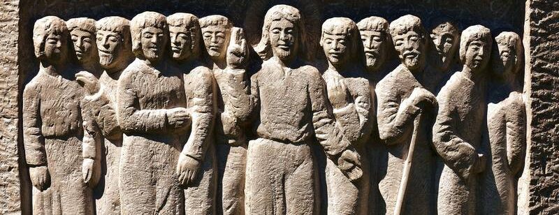 Steinrelief, das 13 Personen in langen Gewändern zeigt, die dicht beieinander stehen. Gesichter und Kleidung sind aufwendig verziert. In der Mitte steht Christus , rechts und links je 6 Personen.